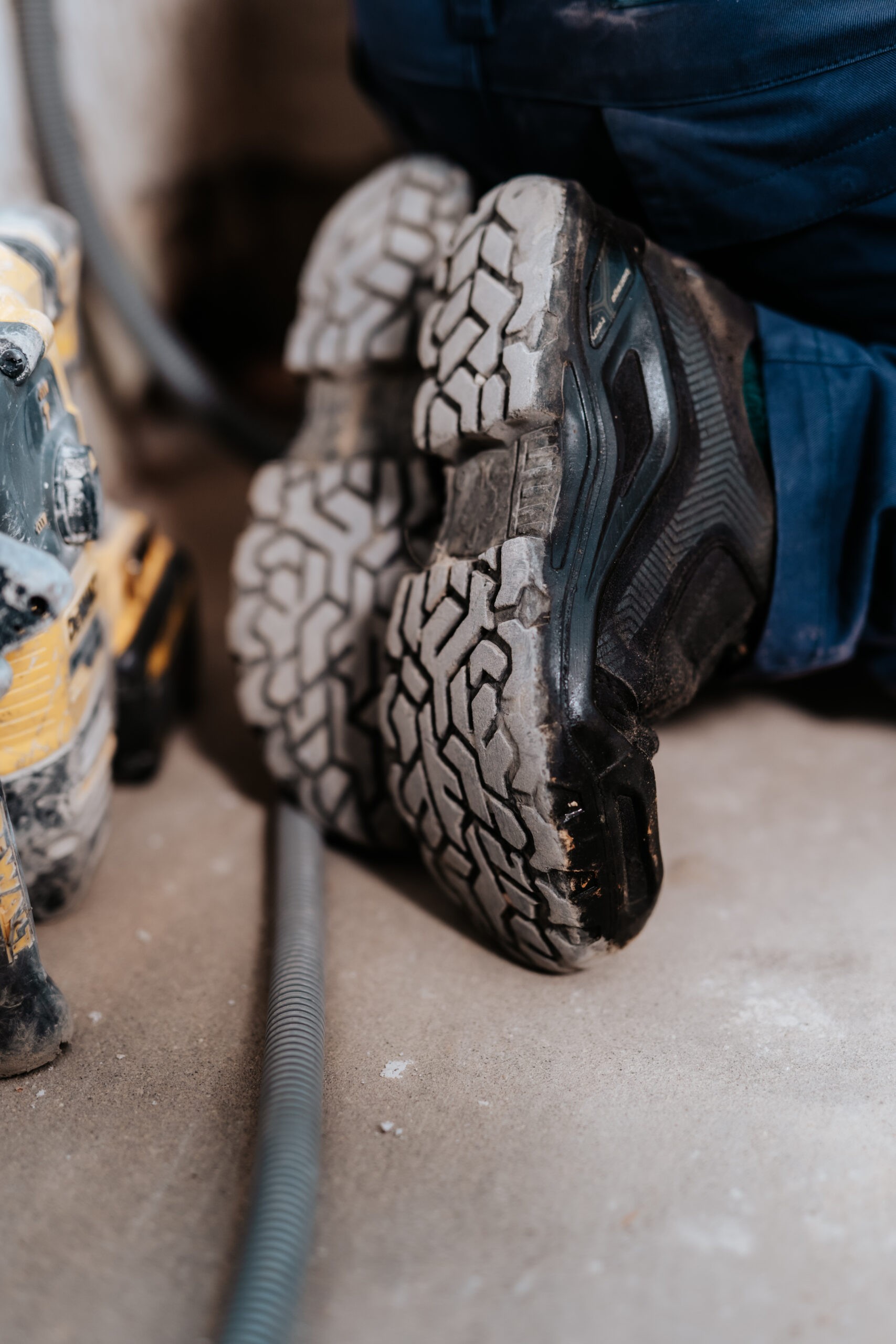 Staubige Schuhsohle von am Boden knieendem Installateur.